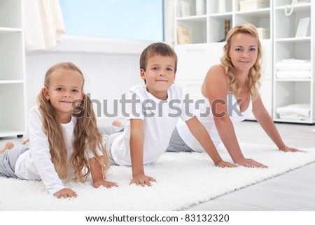 Woman and kids stretching their backs doing gymnastic exercises at home - focus on the boy