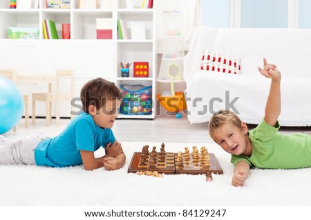 Boy wins chess game against his friend - kids laying on the floor