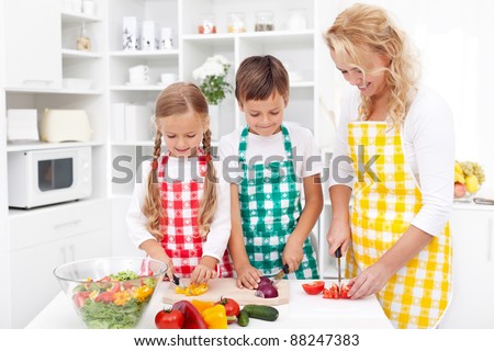 Happy family with aprons preparing healthy fresh salad together
