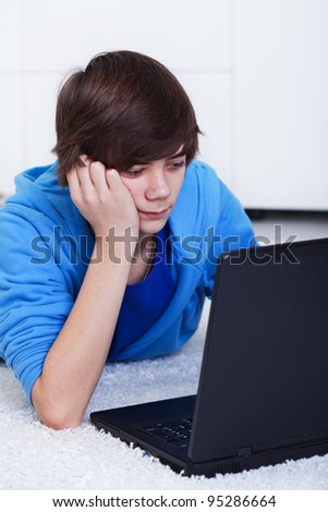 Teenager boy with laptop laying on the floor - computer generation, closeup