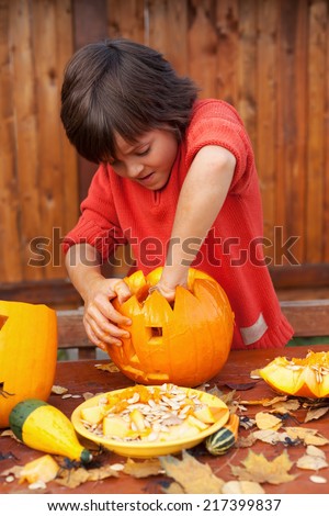 Boy busy carving a pumpkin jack-o-lantern for Halloween - removing the seeds