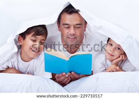 Father reading a story to his little sons - family time together