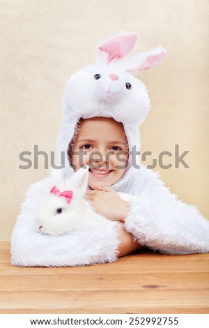 Cute little girl in bunny costume holding her white rabbit - laughing with joy