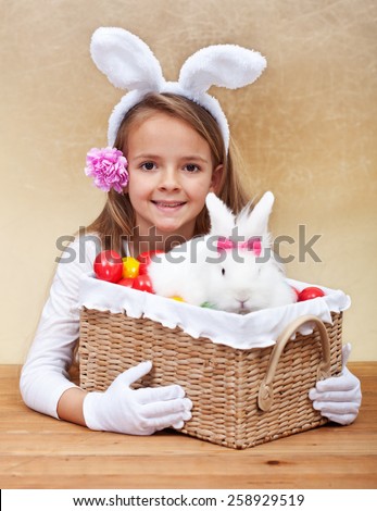 Happy spring girl with easter basket - holding colorful eggs and white rabbit