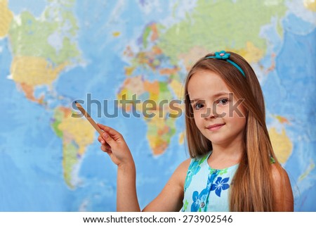 Little student girl pointing to blurry world map with pencil - copy space
