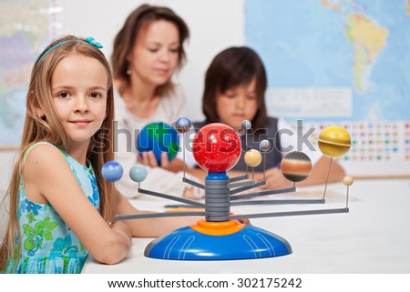 Kids study the solar system under their teacher supervision - focus on the little girl in front