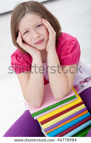 Young girl with headache sitting with lots of books
