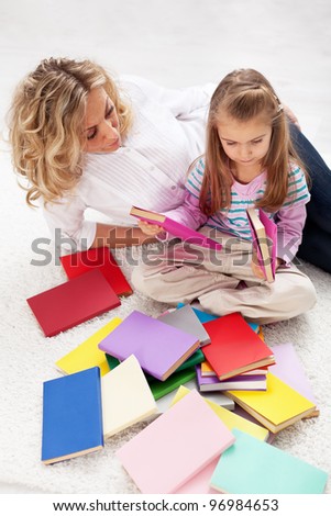 Selecting a story to read - woman and little girl with lots of books