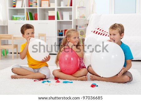 Kids blowing up large balloons indoors