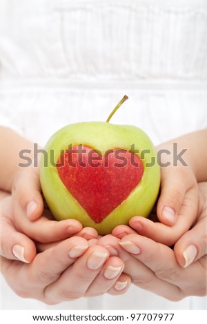 Healthy nutrition concept - hands holding apple with heart cutout