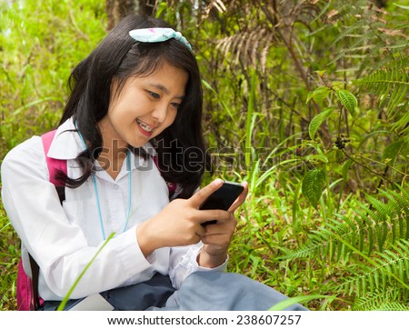 High School student using mobile phone for social media interaction in the park
