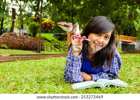Asian girl smiling with book and study in the park