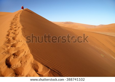 Tourist walking up a dune in Sossusvlei, Namib Naukluft National Park, Namib desert, Namibia.