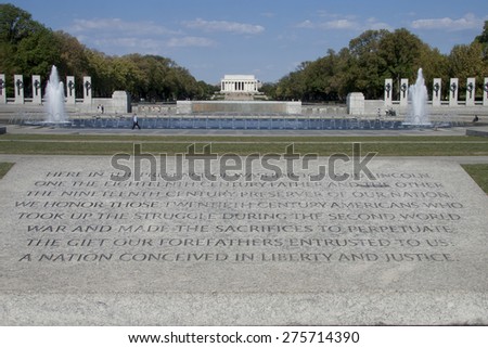 World War II Memorial on the national mall in Washington, D.C. with inscription in foreground and Lincoln Memorial in background.