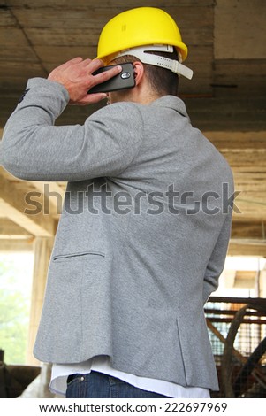 Engineer at a construction site making a business call