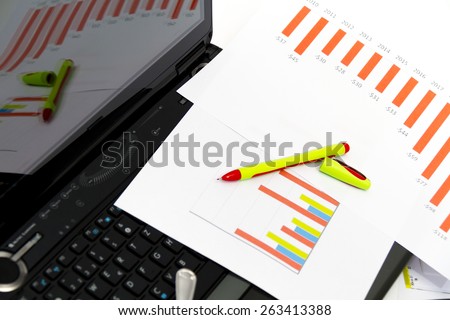 Analyzing business investment charts with calculator and laptop