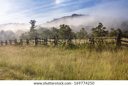 Landscape of split rail fence shrouded in fog along the Blue Ridge Parkway in Western North Carolina.