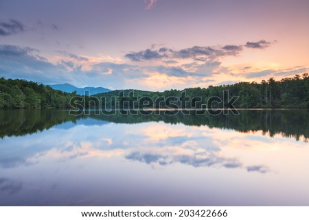 Sunset sky and clouds reflecting in the water at Julian Price Lake in Western North Carolina in evening light.