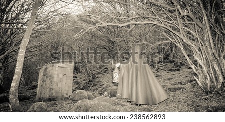 Dark woman with cape walking in the forest