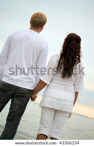 couple holding hands in sunset. stock photo : couple holding hands watching the sunset