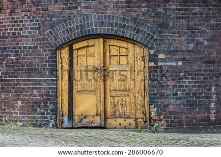 Old wooden door embedded in a brick wall chimney./Entrance.