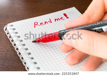 Read me sign in the notebook by red marker in the hand
