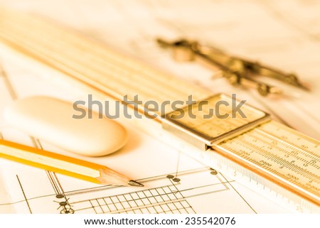 Preparation for drafting papers, the tools and schemes on the table. Angle view, focus on a pencil, in yellow tone
