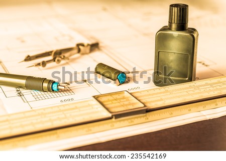 Slide rule with diagrams and drawing tools on the table. Angle view, in yellow tone