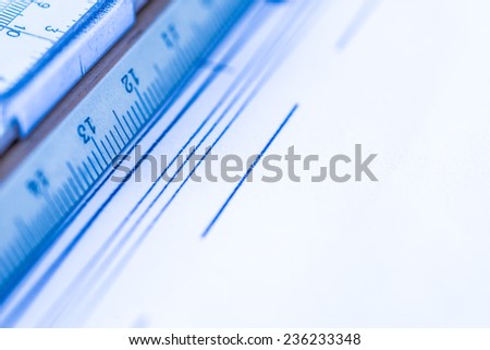 Schemes and slide rule on the table. Angle view close-up, in blue tone