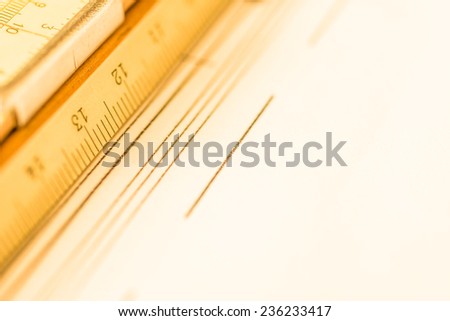 Schemes and slide rule on the table. Angle view close-up, in yellow tone