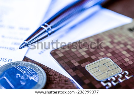 Pay the bills, credit card with pen and money on the table. In blue tone