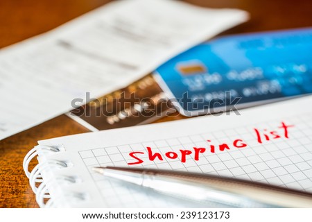 Shopping list, a notebook with shopping list and a credit cards with a check on the table