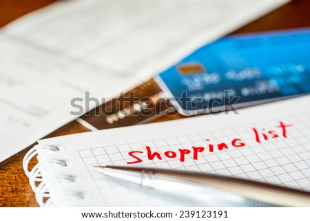 Shopping list, a notebook with shopping list and a credit cards with a check on the table