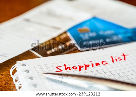 Shopping list, a notebook with shopping list and a credit cards with a checks on the table