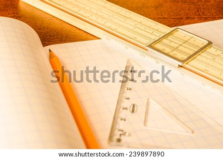 Schemes the pencil and triangle with slide rule on the table in the school. In yellow tone