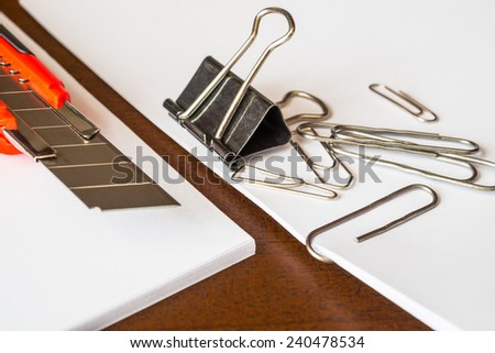 Stationery on the desk in the office, a knife on the paper with a clips
