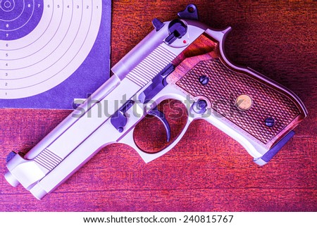 Target shooting, the gun and the target on the table. Top view, in red tone