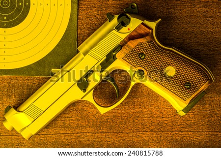 Target shooting, the gun and the target on the table. Top view, ni yellow tone