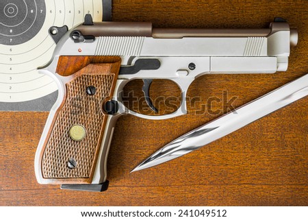 Target shooting, the gun and the target with the knife on the table. Top view