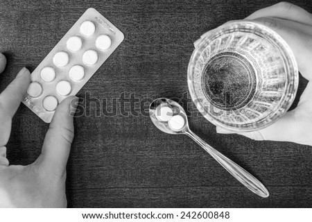 Cure the disease, take the pills in the spoon and drink water. Top view, in black and white tone