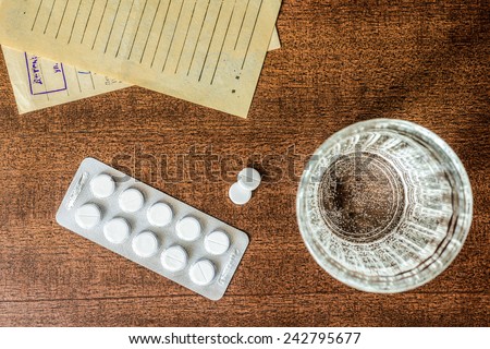 Cure the disease, tablets with a glass of water and prescriptions from the doctor on the table. Top view, in the old colors