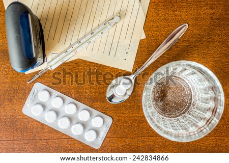 Cure the disease, tablets in the spoon with a glass of water and prescriptions from the doctor and stamp on the table. Top view