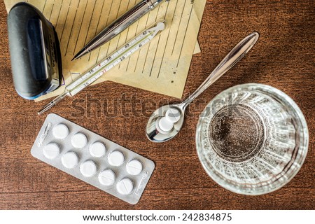 Cure the disease, tablets in the spoon with a glass of water and prescriptions from the doctor and stamp on the table. Top view, in the old tones
