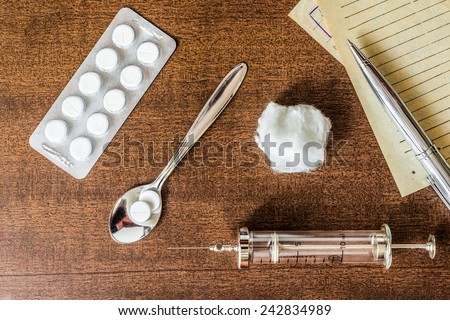 Prescription for the treatment of the disease, a tablets with a syringe on the table. Top view, in the old tones