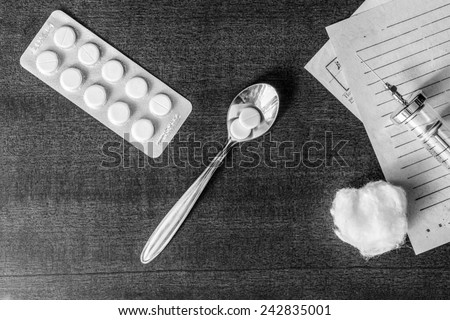 Prescription for the treatment of the disease, a tablets with a syringe on the table. Top view, in the black and white tones