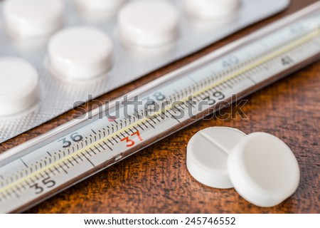 Cure the disease, measure temperature by thermometer and take the pills. Angle view