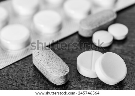 Cure the disease, take the pills and vitamins on the table. Angle view, in black and white tones