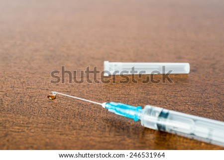Medicine flows from the syringe and spread out on the table. Angle view