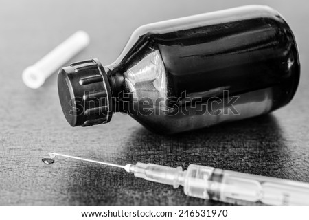 Cure the disease, a solution and a syringe for injection, drug flow from the syringe. Angle view, in black and white tones