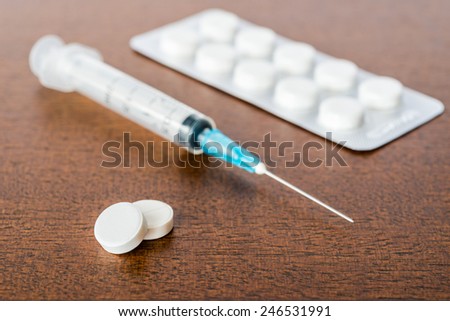 Cure the disease, an injection syringe and take the pills. Angle view